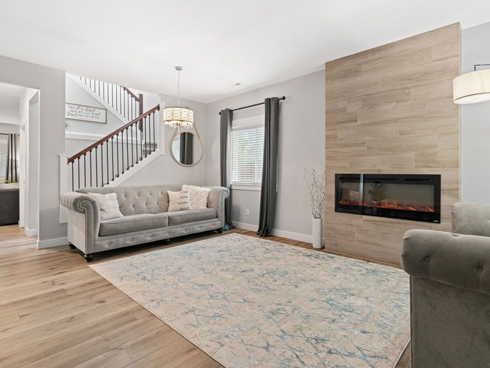 A living room with a couch , chair , rug and fireplace.