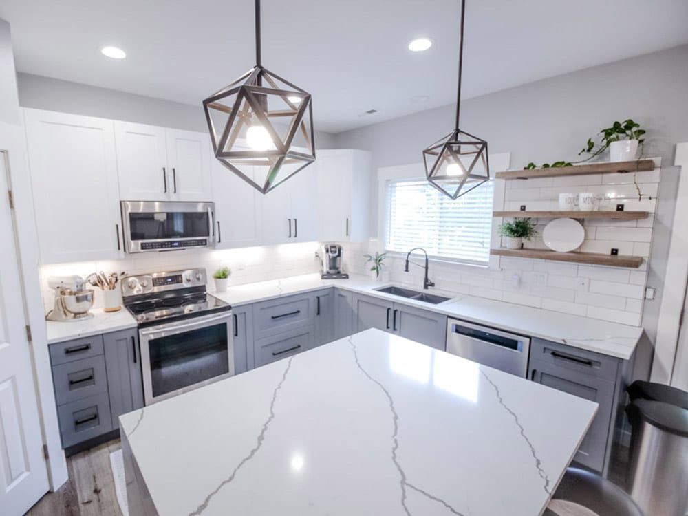 A kitchen with white cabinets , stainless steel appliances , and a large island.