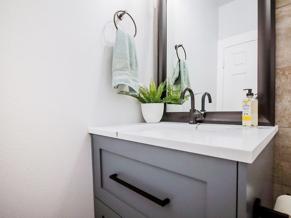 A bathroom with a sink , mirror and towels hanging on the wall.