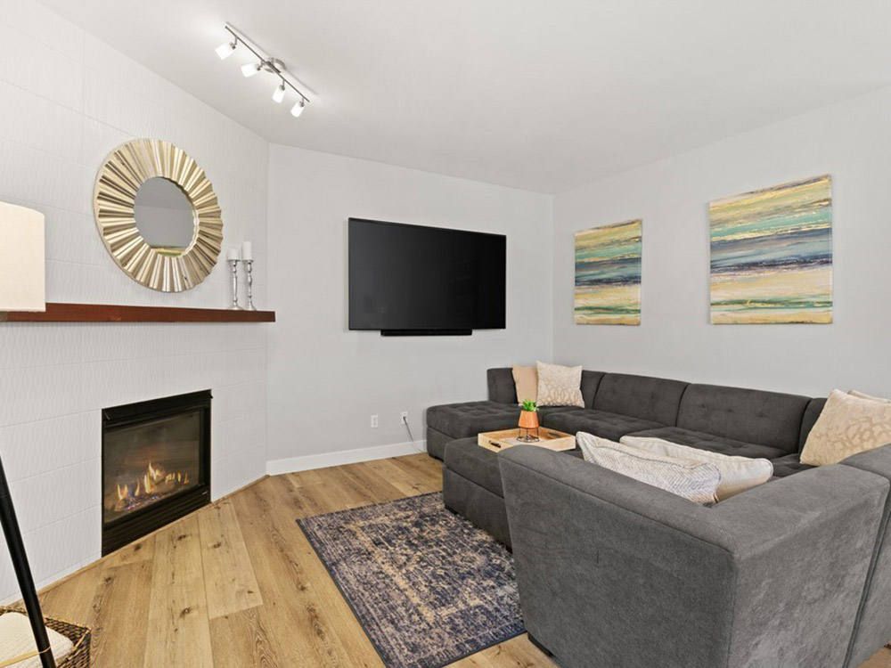 A living room with a couch , fireplace , television and mirror.