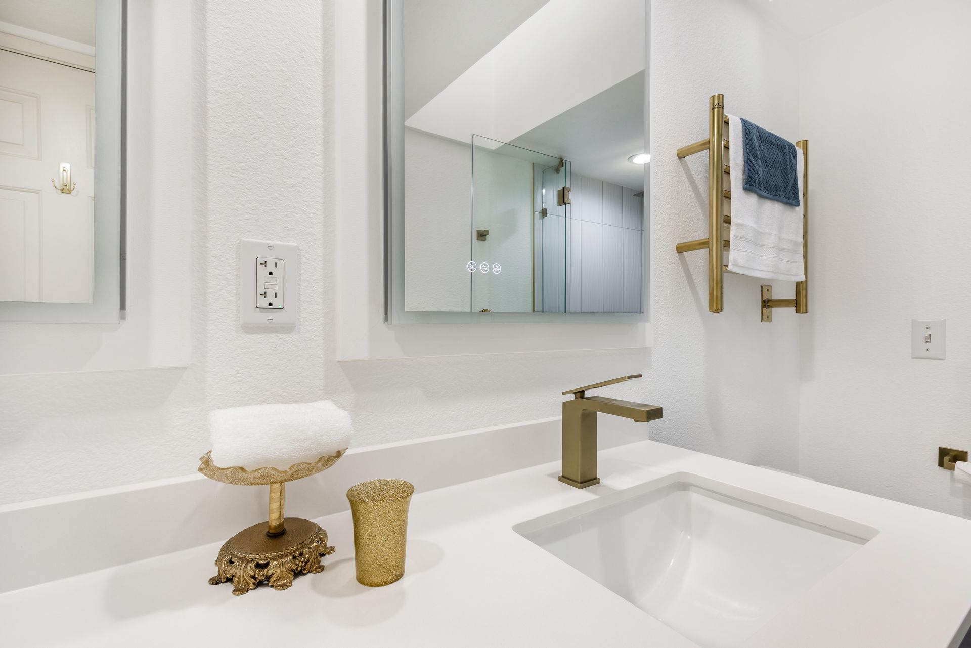 A bathroom with a sink , mirror and towel rack.