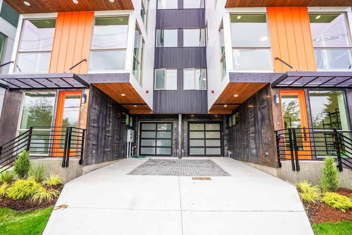 A modern apartment building with a concrete walkway leading to the entrance.
