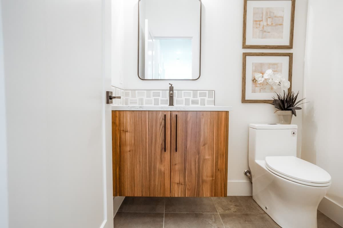 A bathroom with a toilet , sink and mirror.