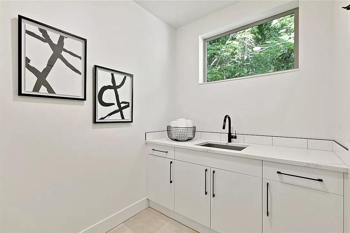 A laundry room with a sink , cabinets , and a window.