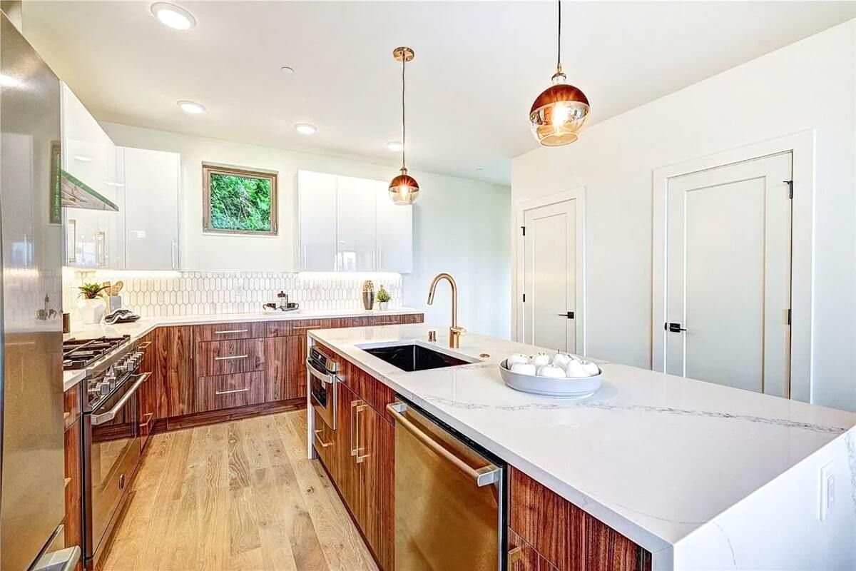 A kitchen with wooden cabinets , white counter tops , stainless steel appliances and a large island.