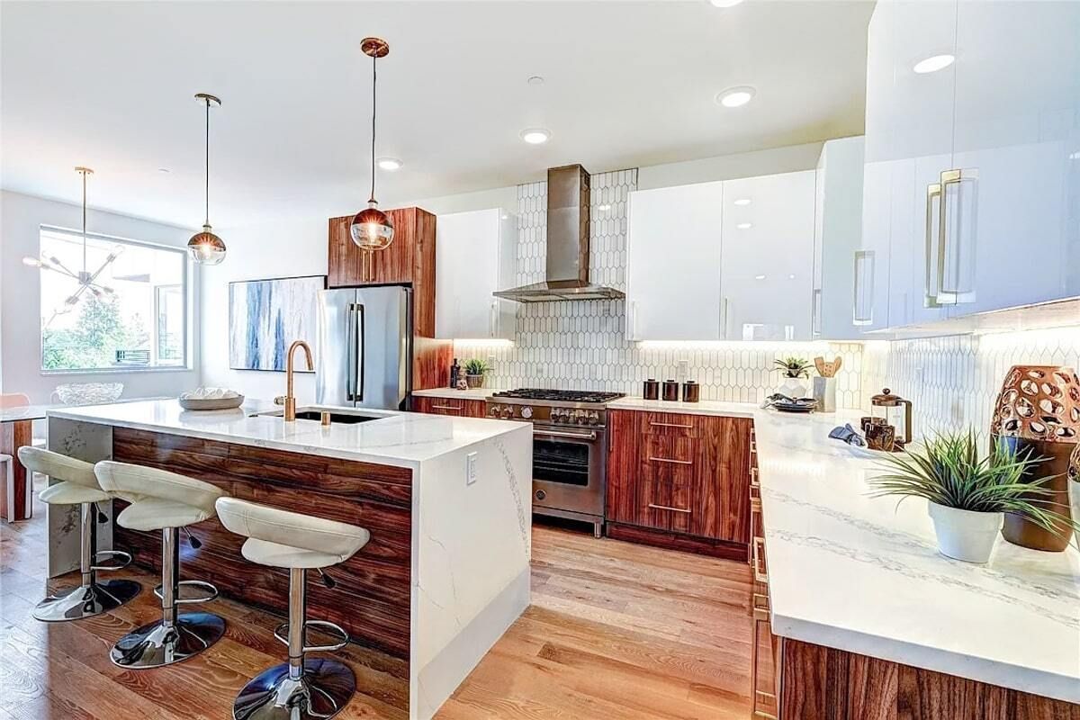 A kitchen with white cabinets , wooden cabinets , stainless steel appliances and a large island.