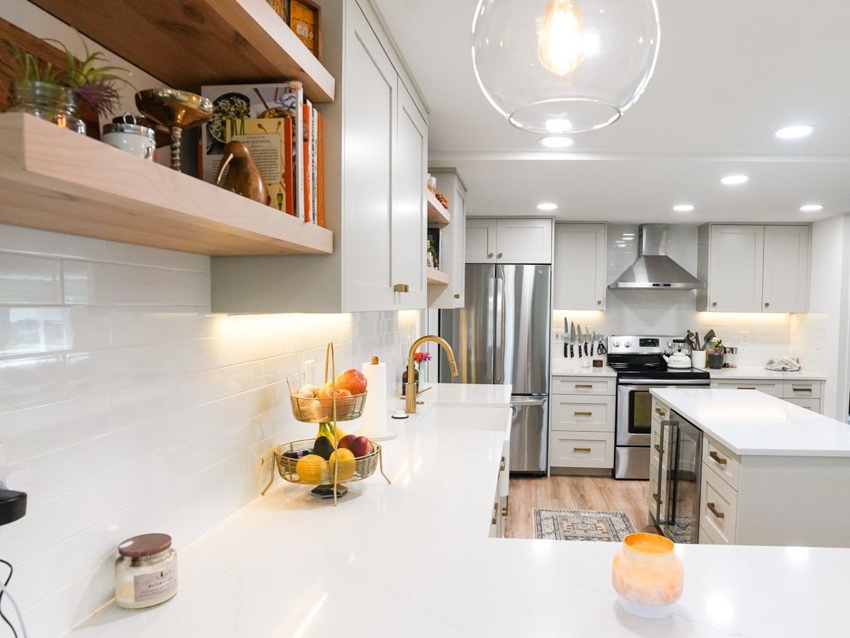 A kitchen with white cabinets , stainless steel appliances , and a fruit basket on the counter.