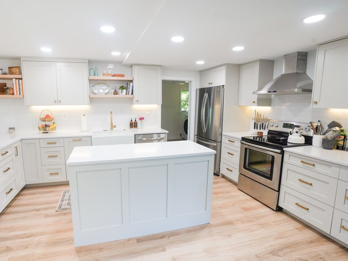 A kitchen with white cabinets , stainless steel appliances , and a large island.