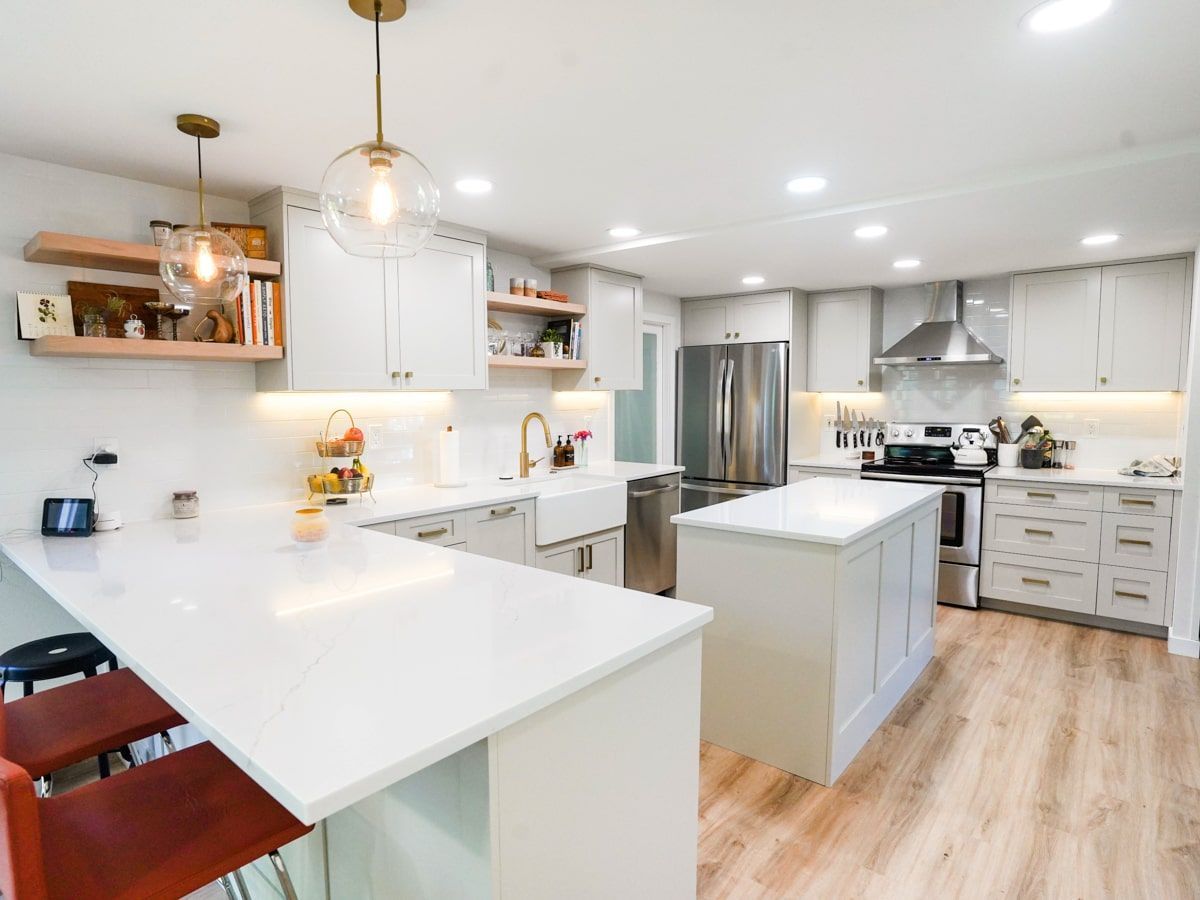 A kitchen with white cabinets , stainless steel appliances , and a large island.