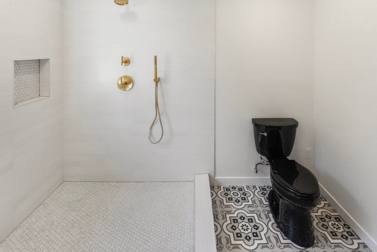 A bathroom with a black toilet and a walk in shower.