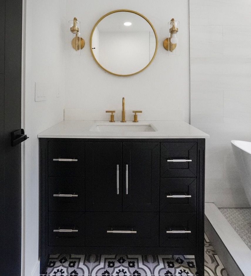A bathroom with a black vanity a sink and a mirror