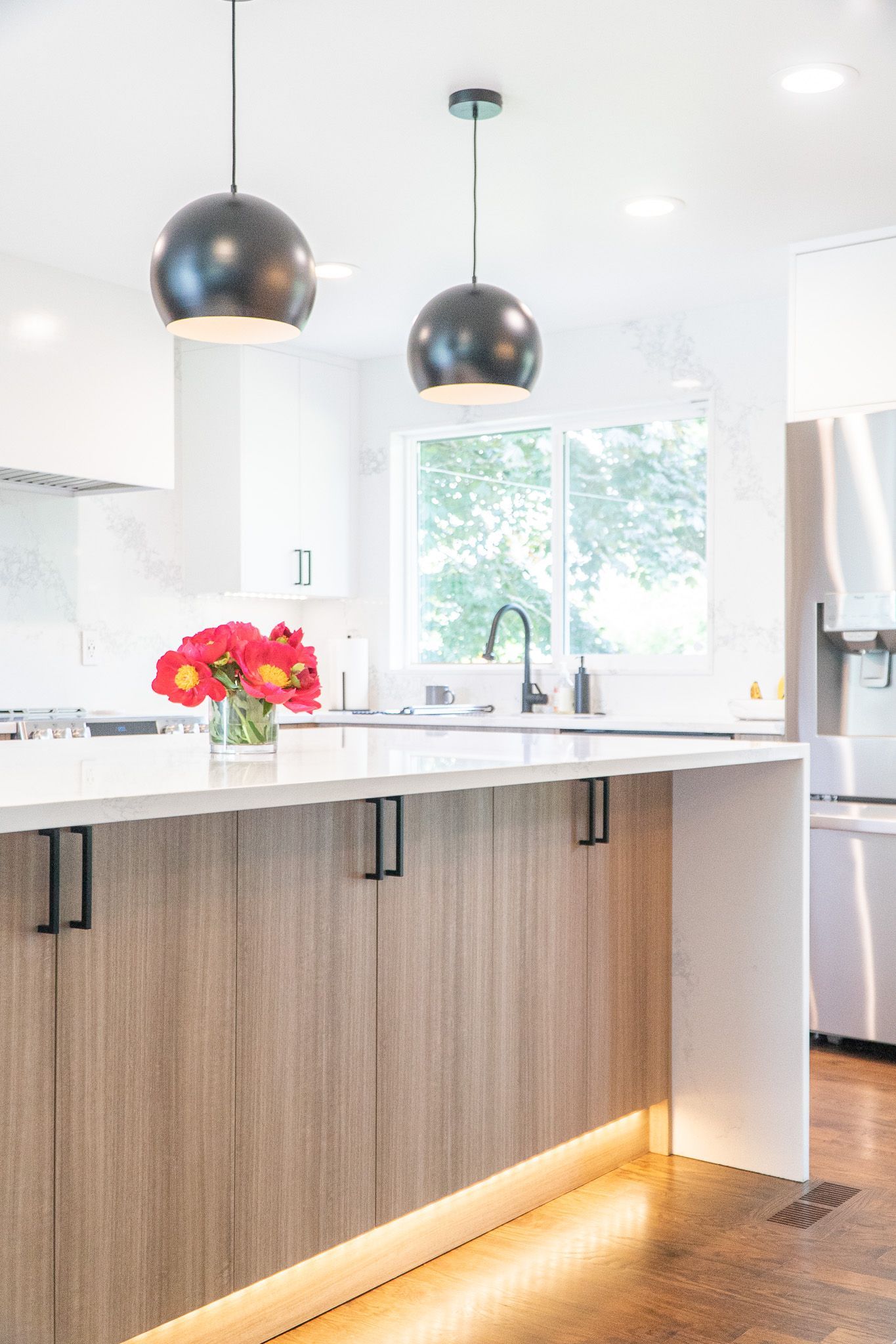 There is a vase of flowers on the counter in the kitchen.