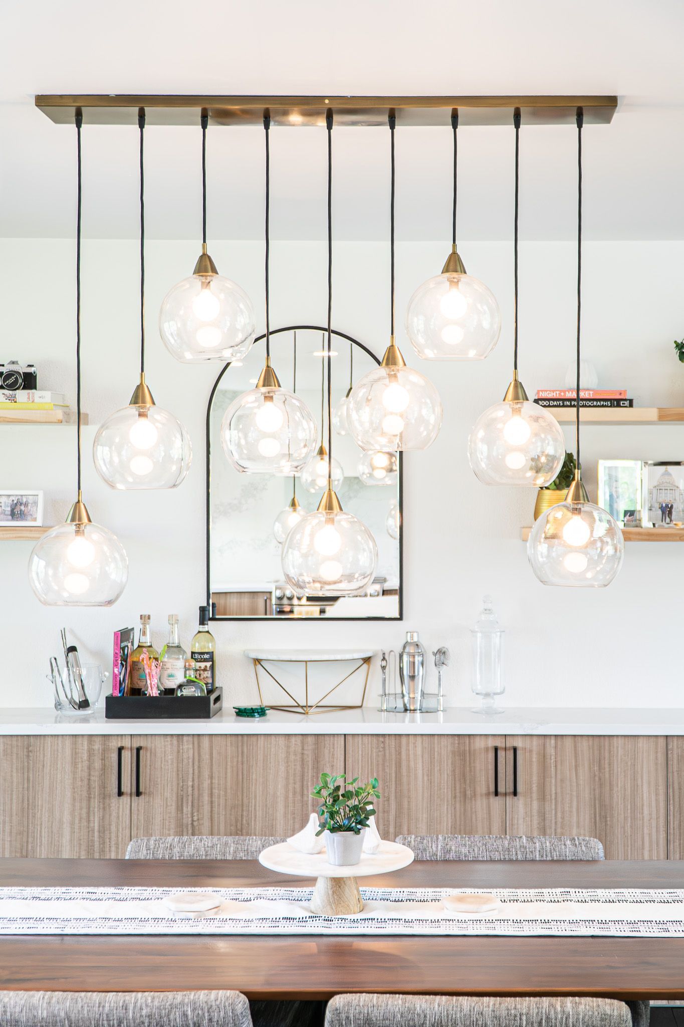A dining room with a table , benches , cabinets and a mirror.