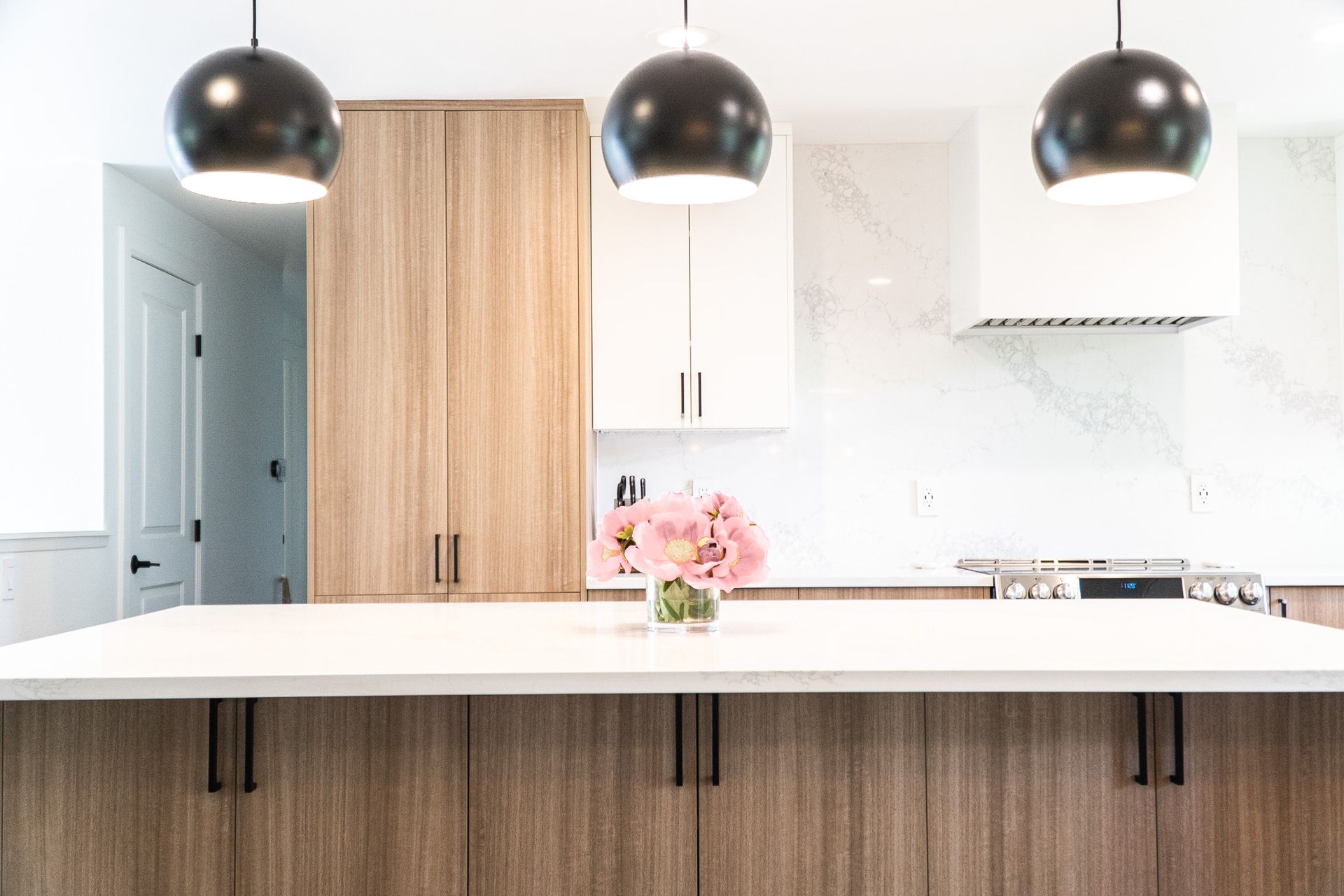 There is a vase of flowers on the counter in the kitchen.
