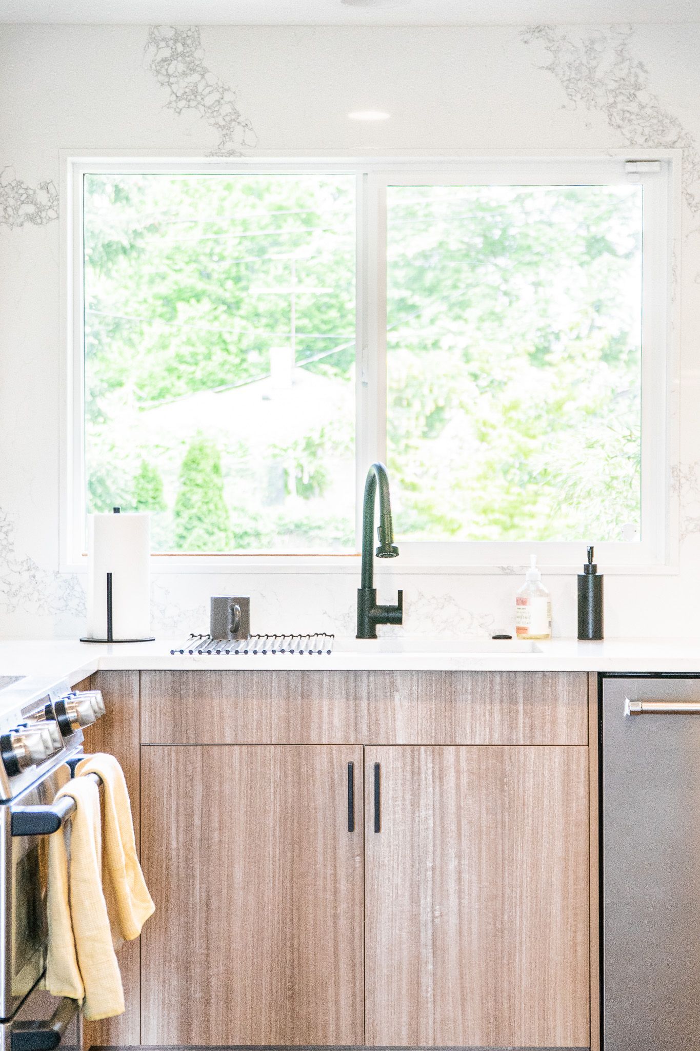 A kitchen with a sink , stove , dishwasher and window.