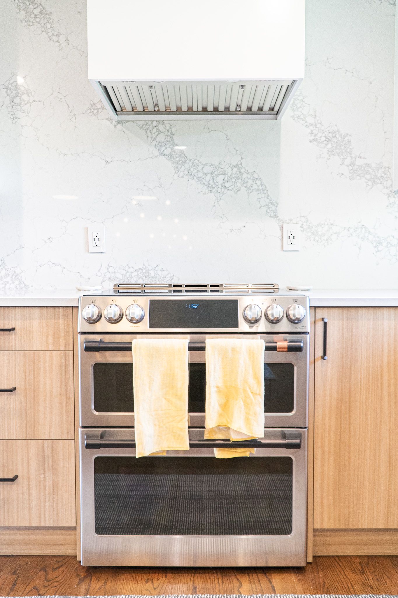 A stainless steel stove with two towels hanging out of it in a kitchen.