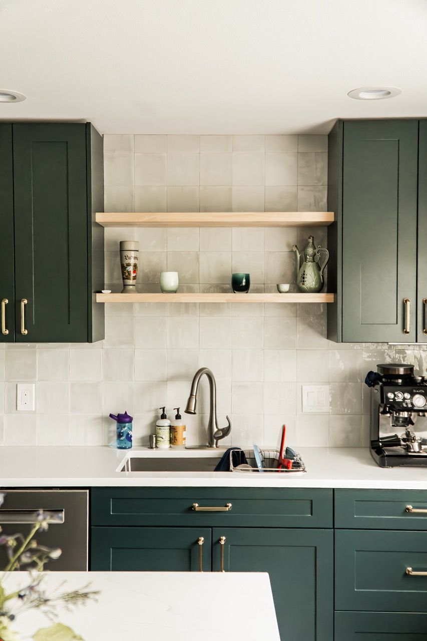A kitchen with green cabinets , a sink , and a coffee maker.