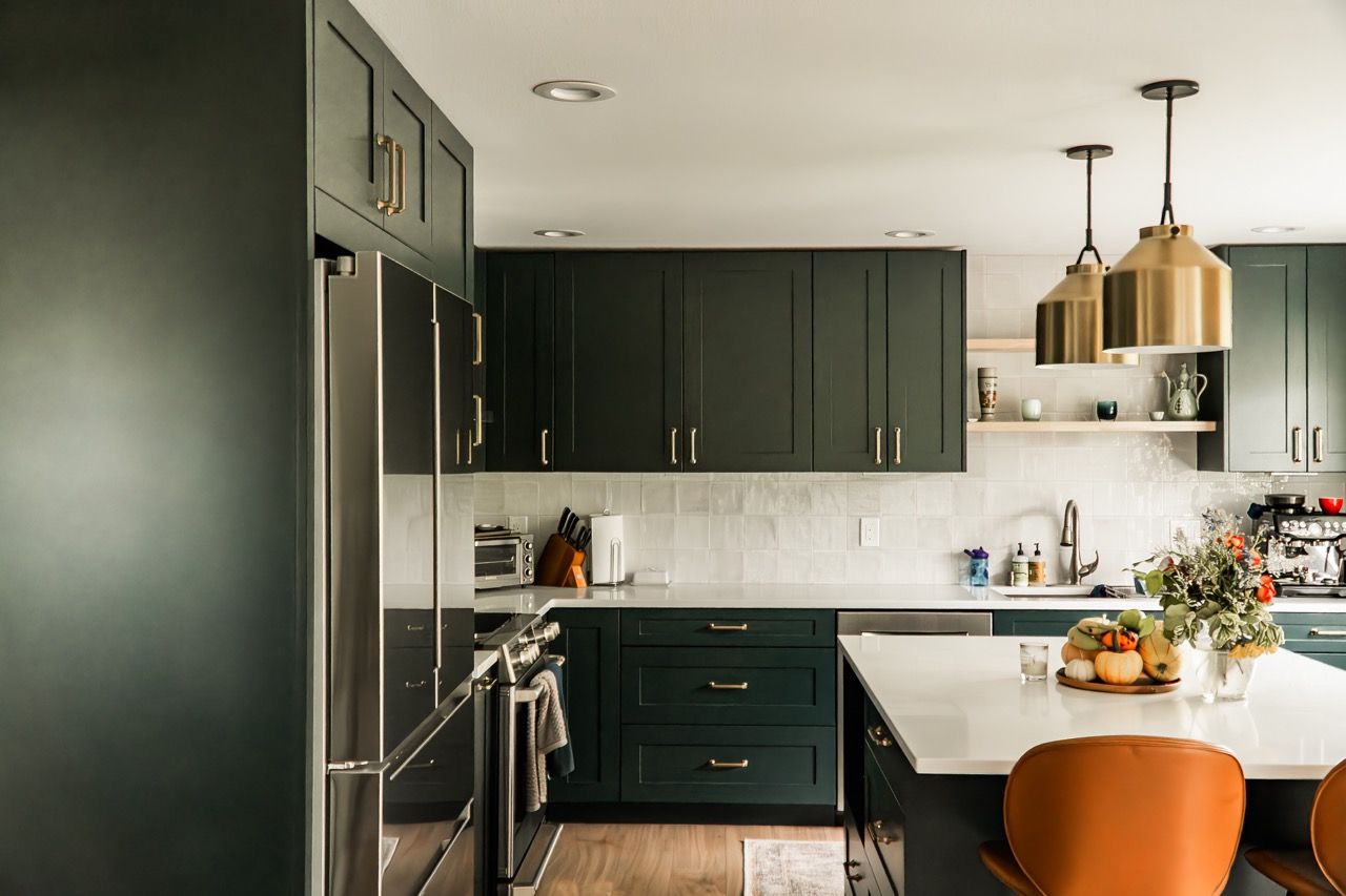 A kitchen with green cabinets , stainless steel appliances , and a large island.