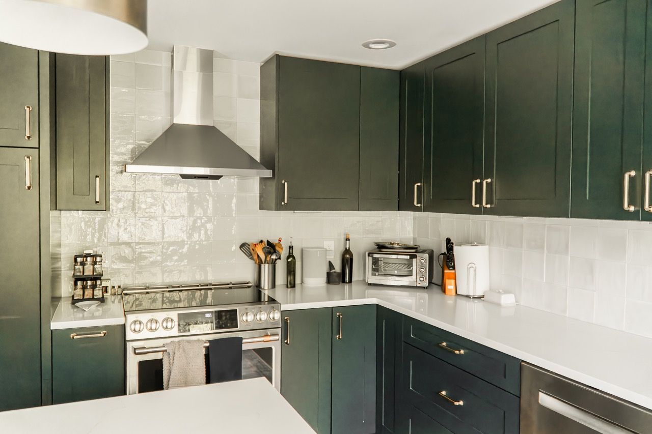 A kitchen with green cabinets and stainless steel appliances