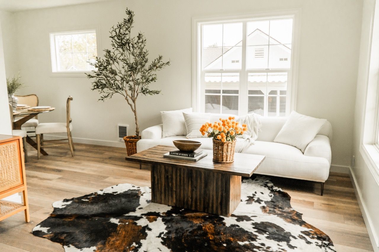 A living room with a couch , coffee table , and cowhide rug.