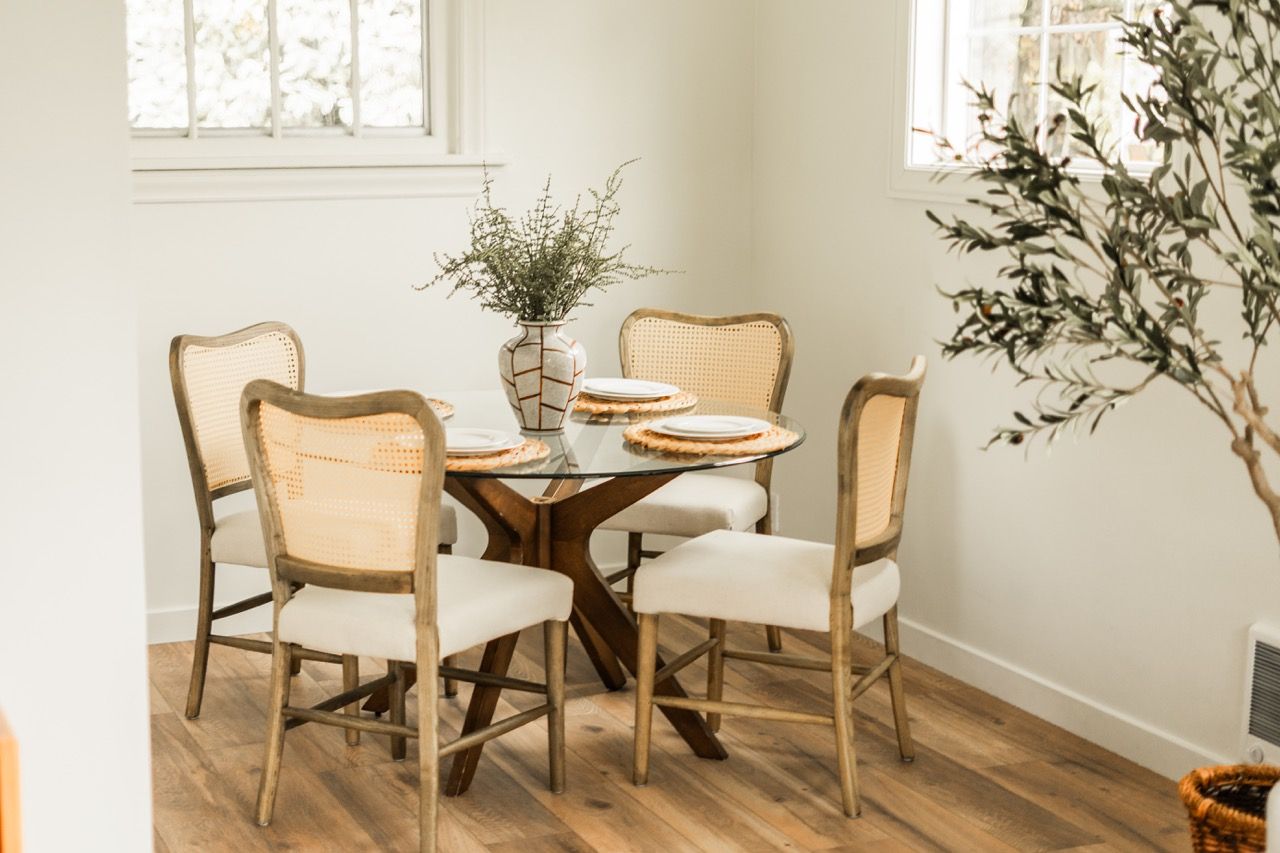 A dining room with a table and chairs and a plant.