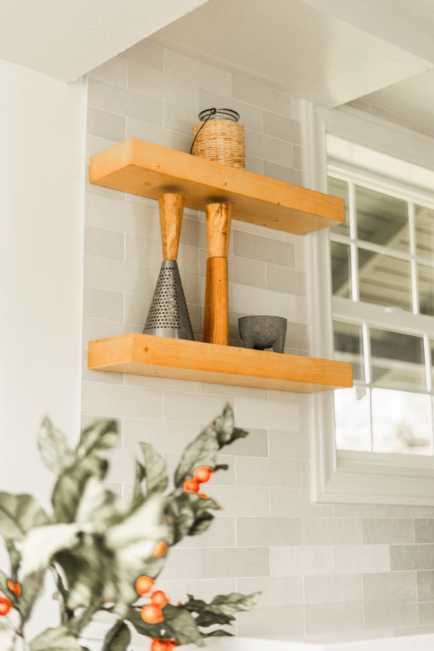 A kitchen with two wooden shelves and a window.