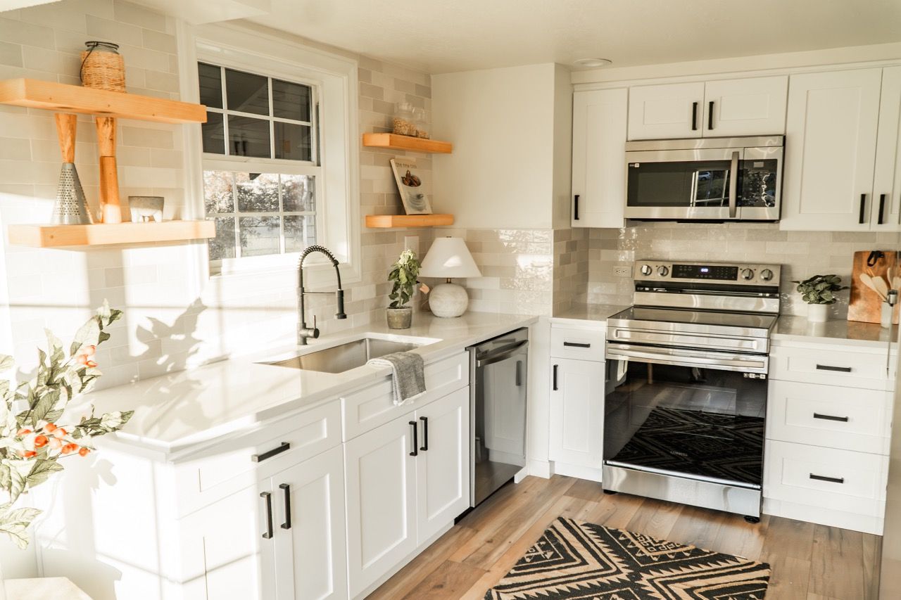 A kitchen with white cabinets , stainless steel appliances , a sink , and a stove.