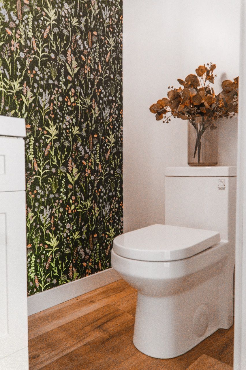 A bathroom with a toilet and a vase of flowers