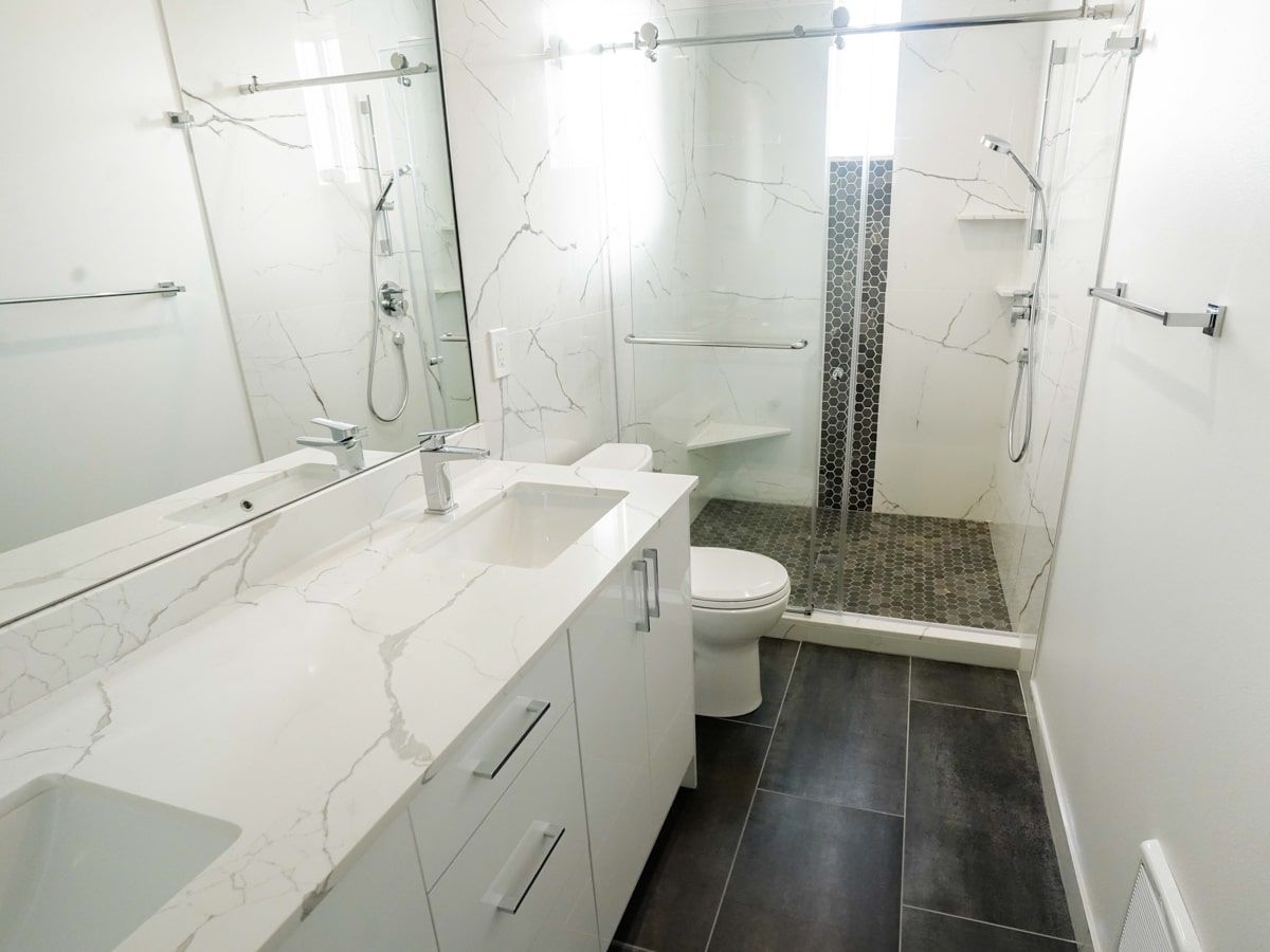 A bathroom with a toilet , sink , mirror and walk in shower.