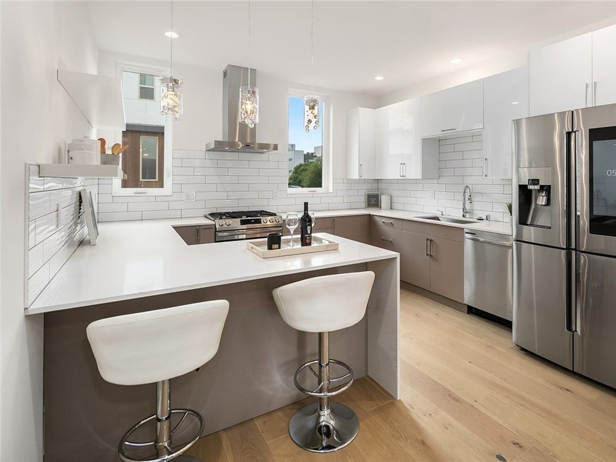 A kitchen with white cabinets , stainless steel appliances , a refrigerator and a stove.