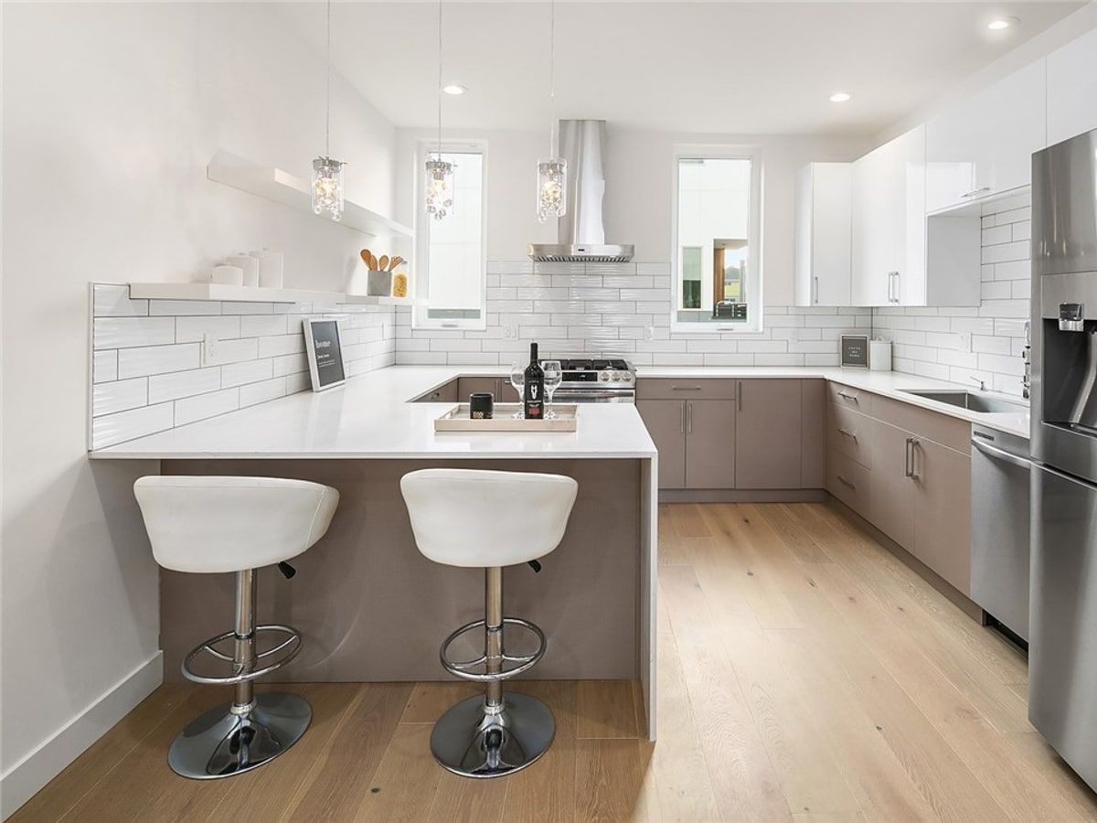 A kitchen with two bar stools and a bottle of wine on the counter.