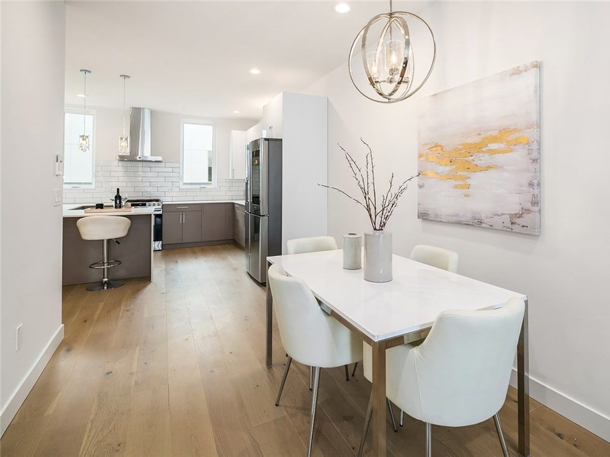 A dining room with a table and chairs and a painting on the wall.