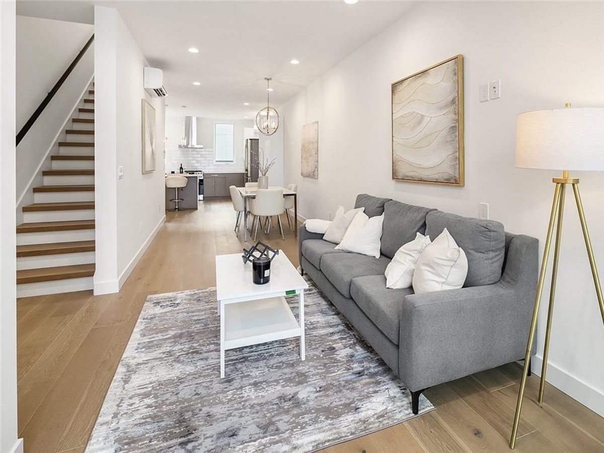 A living room with a couch , coffee table , lamp and stairs.