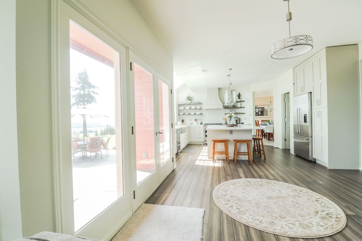 A living room with hardwood floors , sliding glass doors , a rug and a large window.