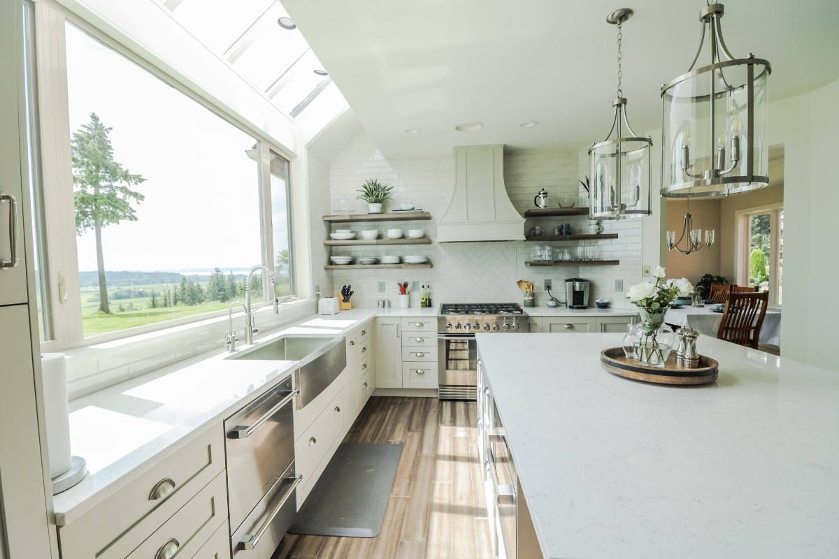 A kitchen with white cabinets , stainless steel appliances , and a large window.