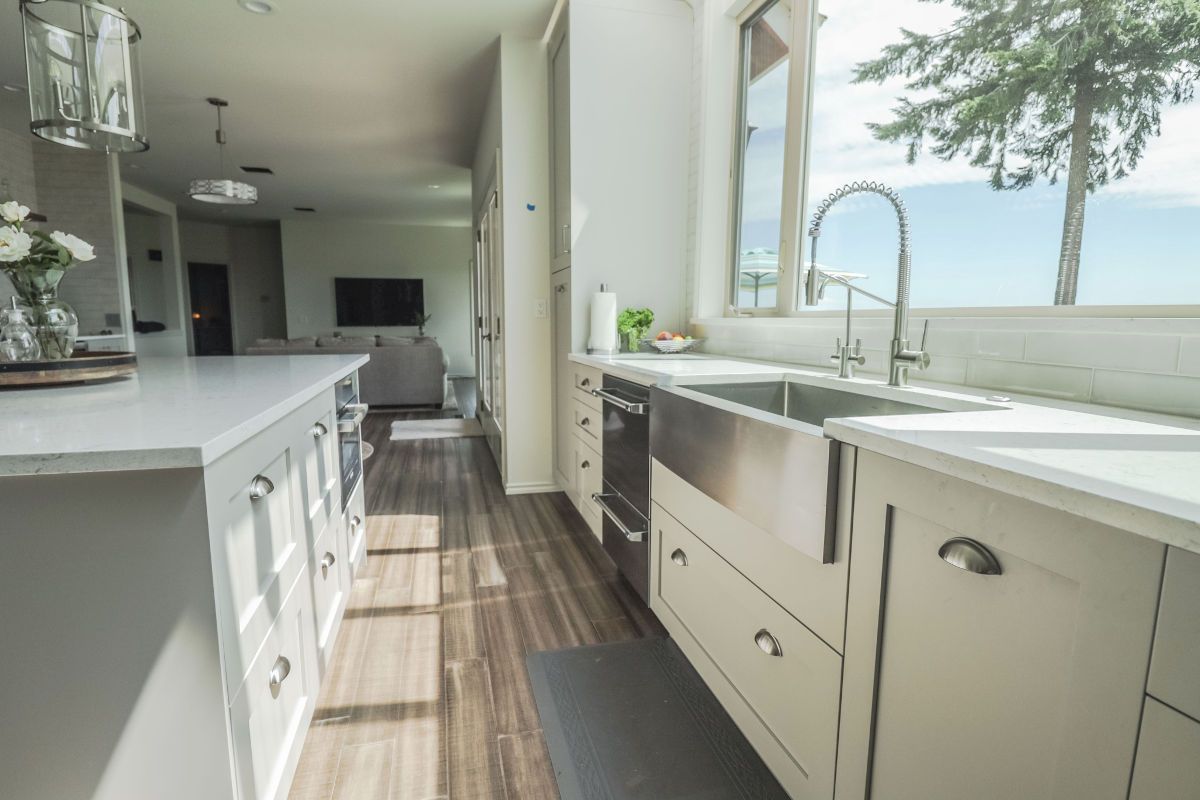 A kitchen with white cabinets and a stainless steel sink.