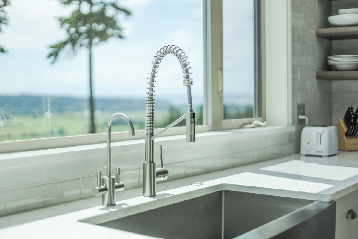 A kitchen sink with a faucet and a window in the background.