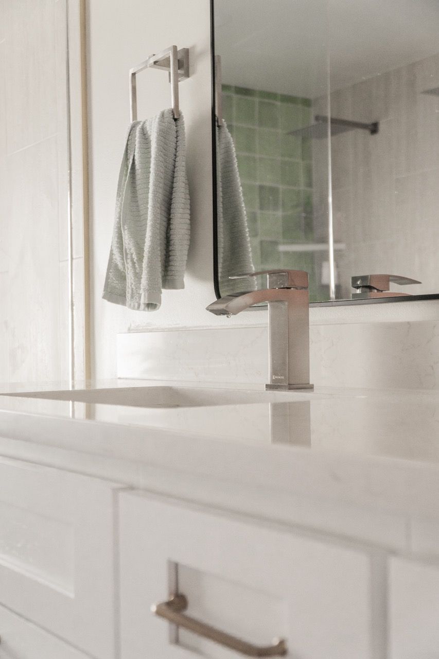A bathroom with a sink , mirror and towels hanging on the wall.
