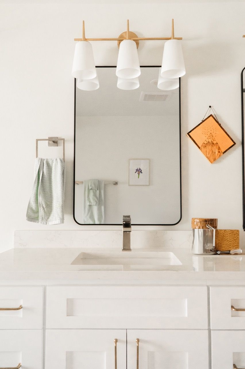 A bathroom with a sink , mirror and light fixture.