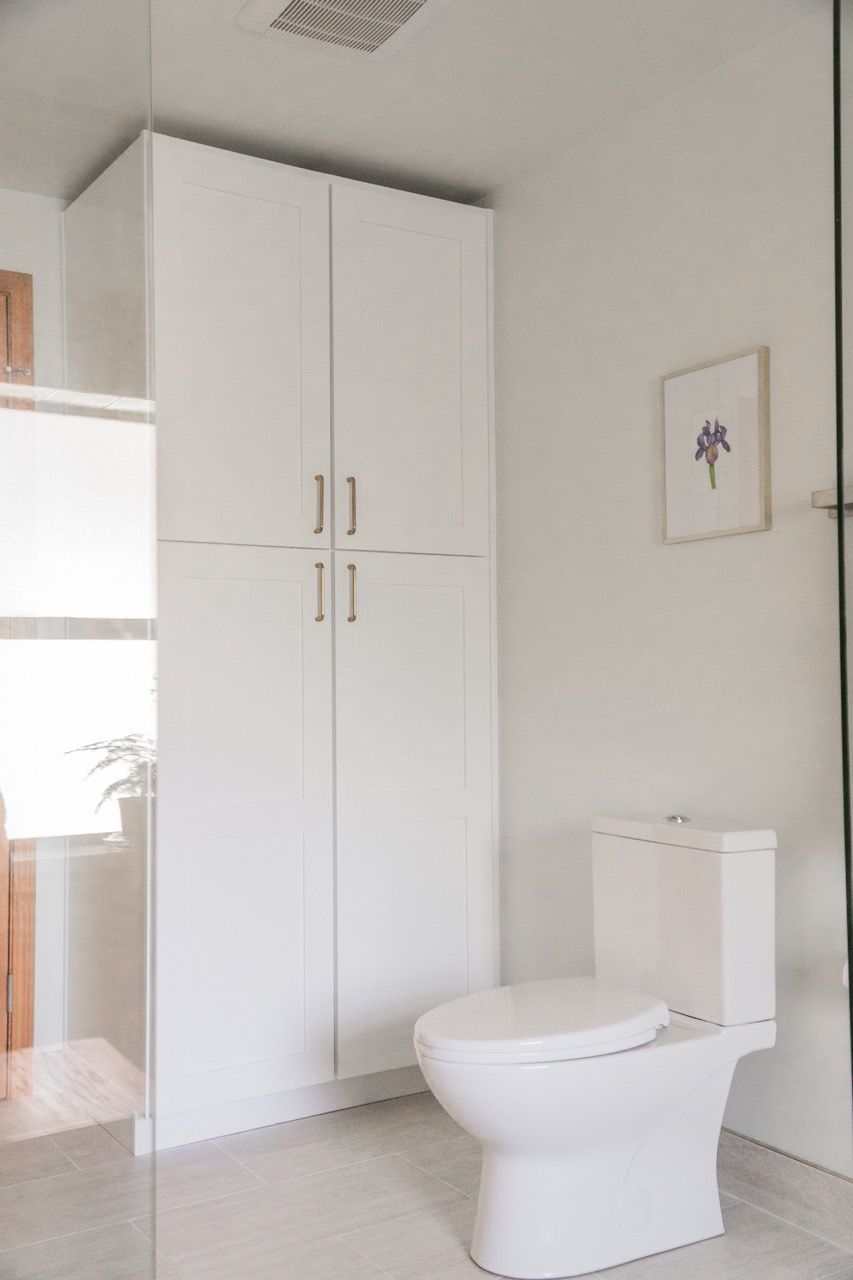A bathroom with a toilet and a cabinet.