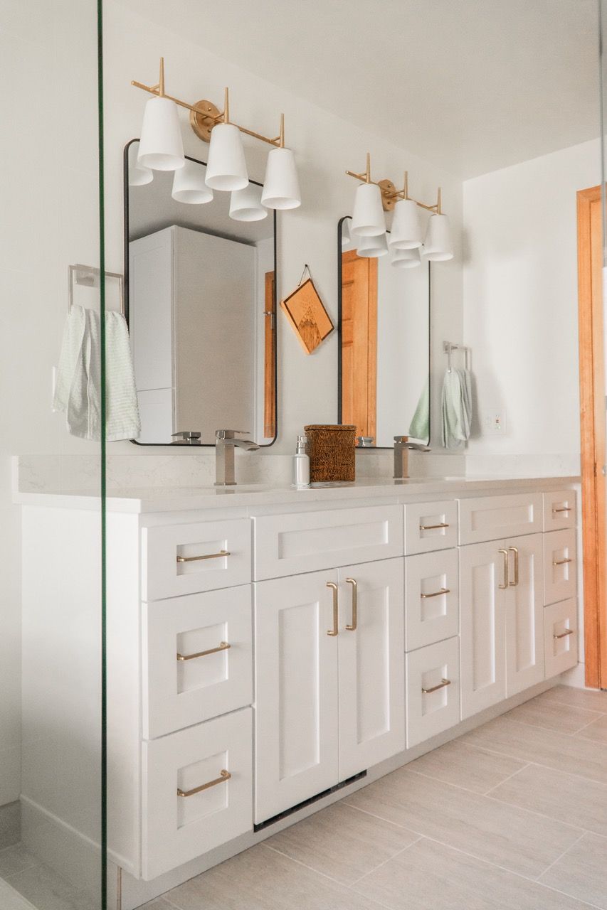 A bathroom with two sinks , two mirrors , and a walk in shower.