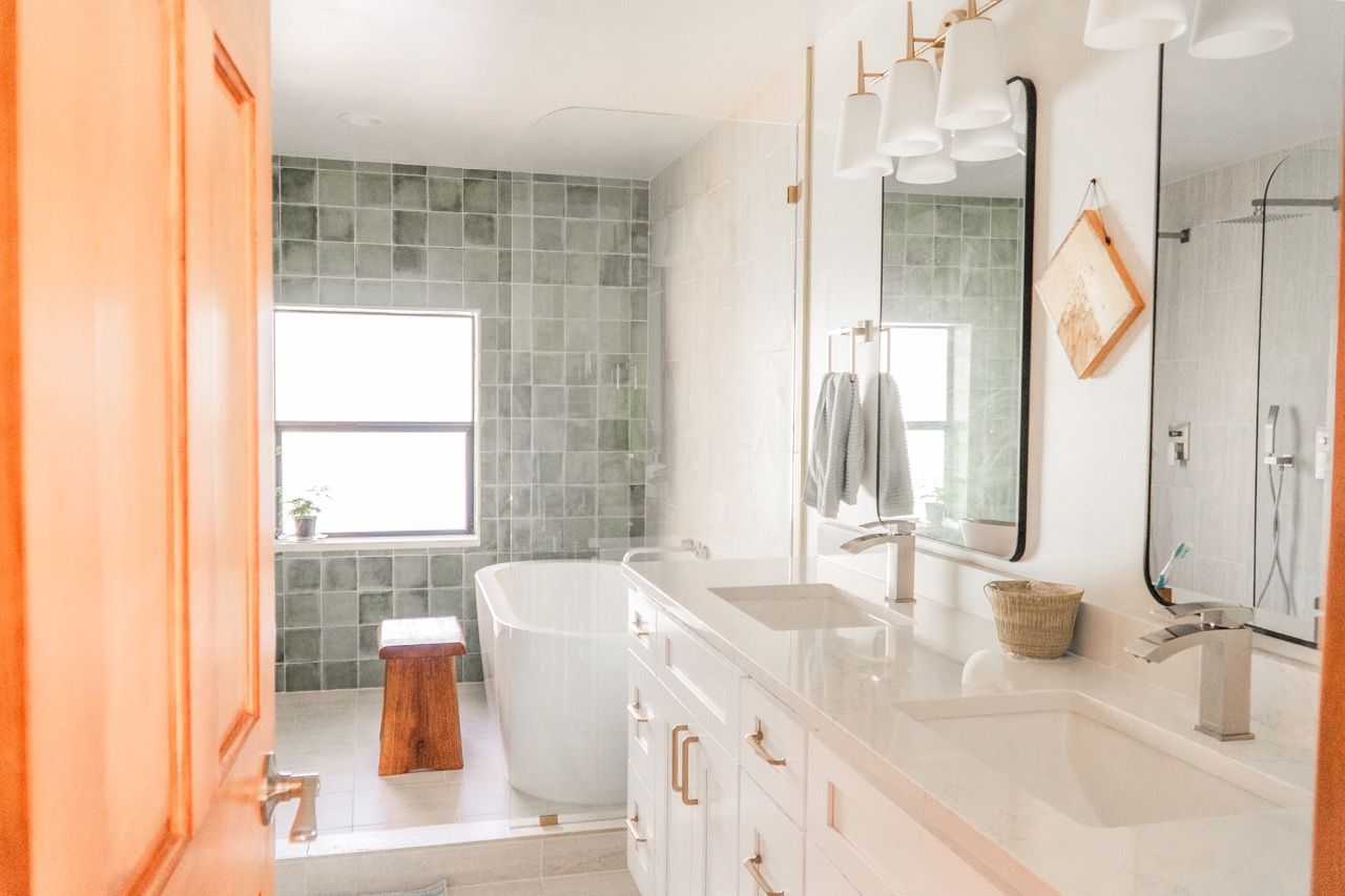 A bathroom with a tub , sink , mirror and window.