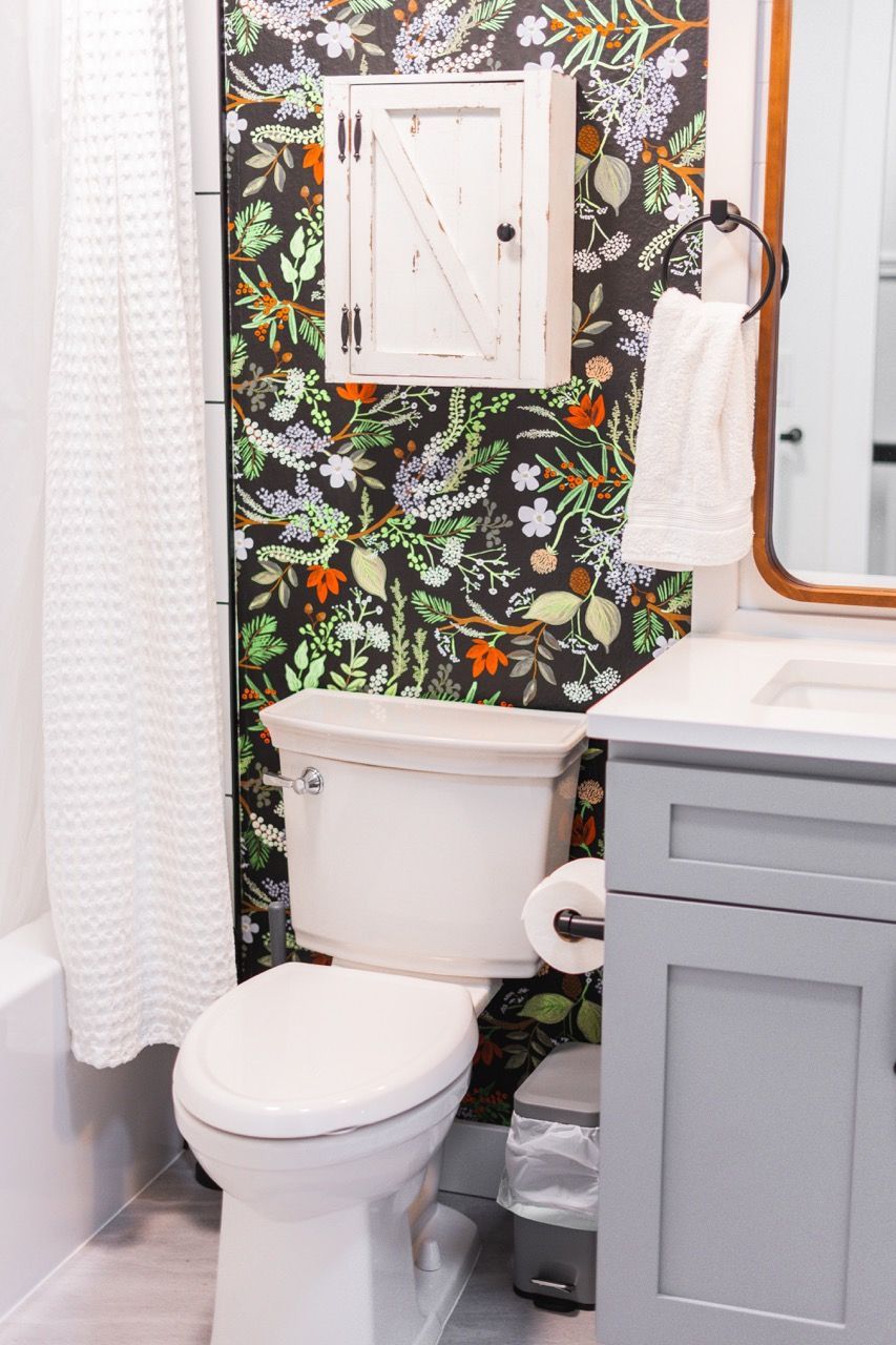 A bathroom with a toilet , sink , mirror and shower curtain.