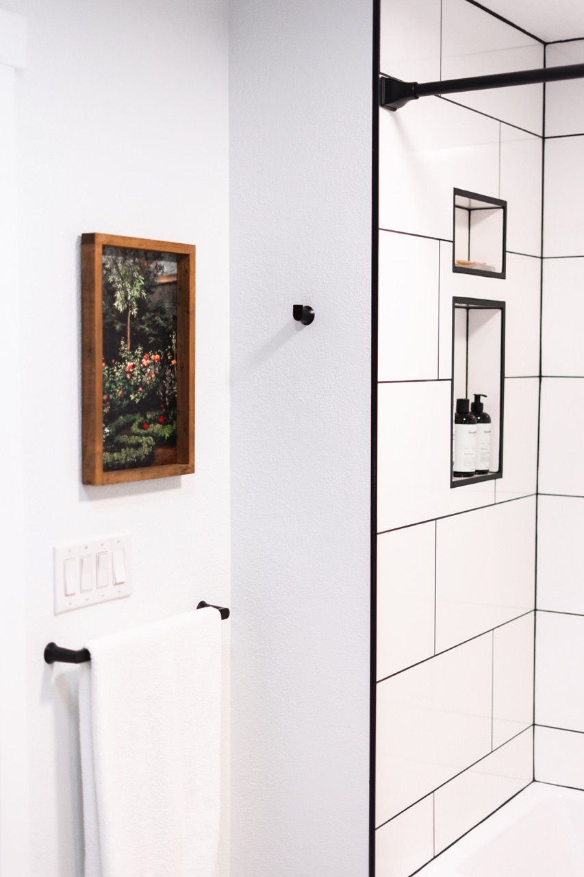 A bathroom with white tiles and a picture on the wall