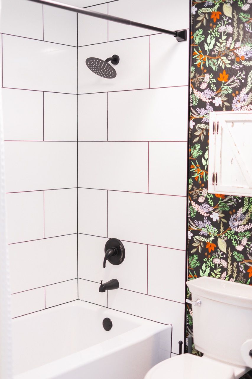 A bathroom with white tiles and floral wallpaper