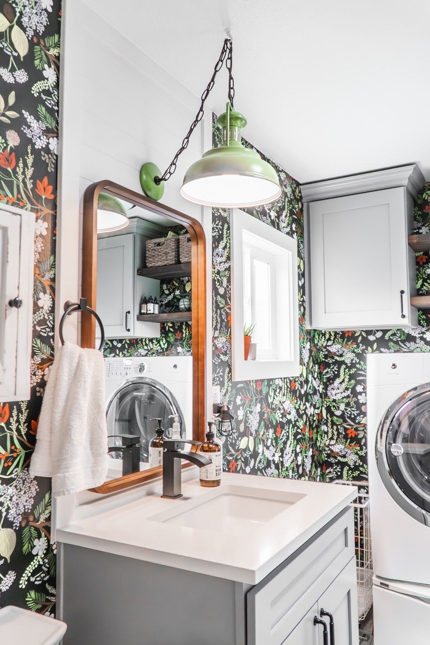 A bathroom with a sink , mirror , washer and dryer.