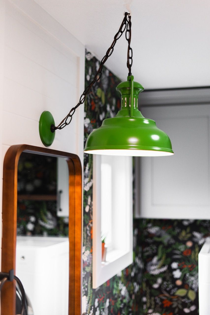 A green light is hanging from the ceiling next to a mirror.