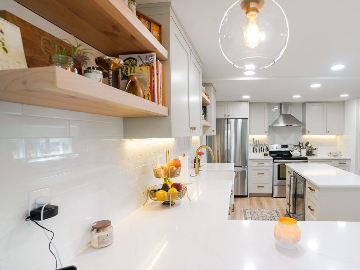 A kitchen with white cabinets , white counter tops , stainless steel appliances and a glass pendant light.