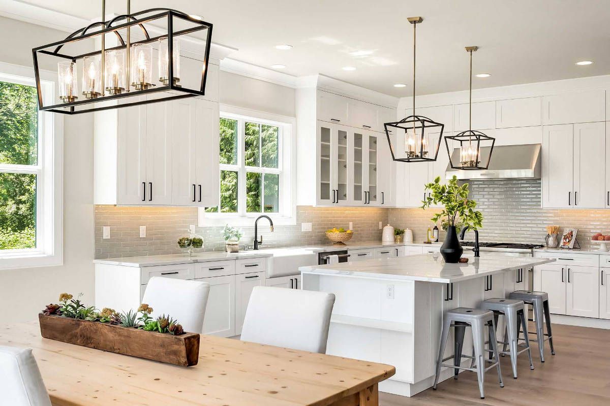 A kitchen with white cabinets and a wooden table and chairs.