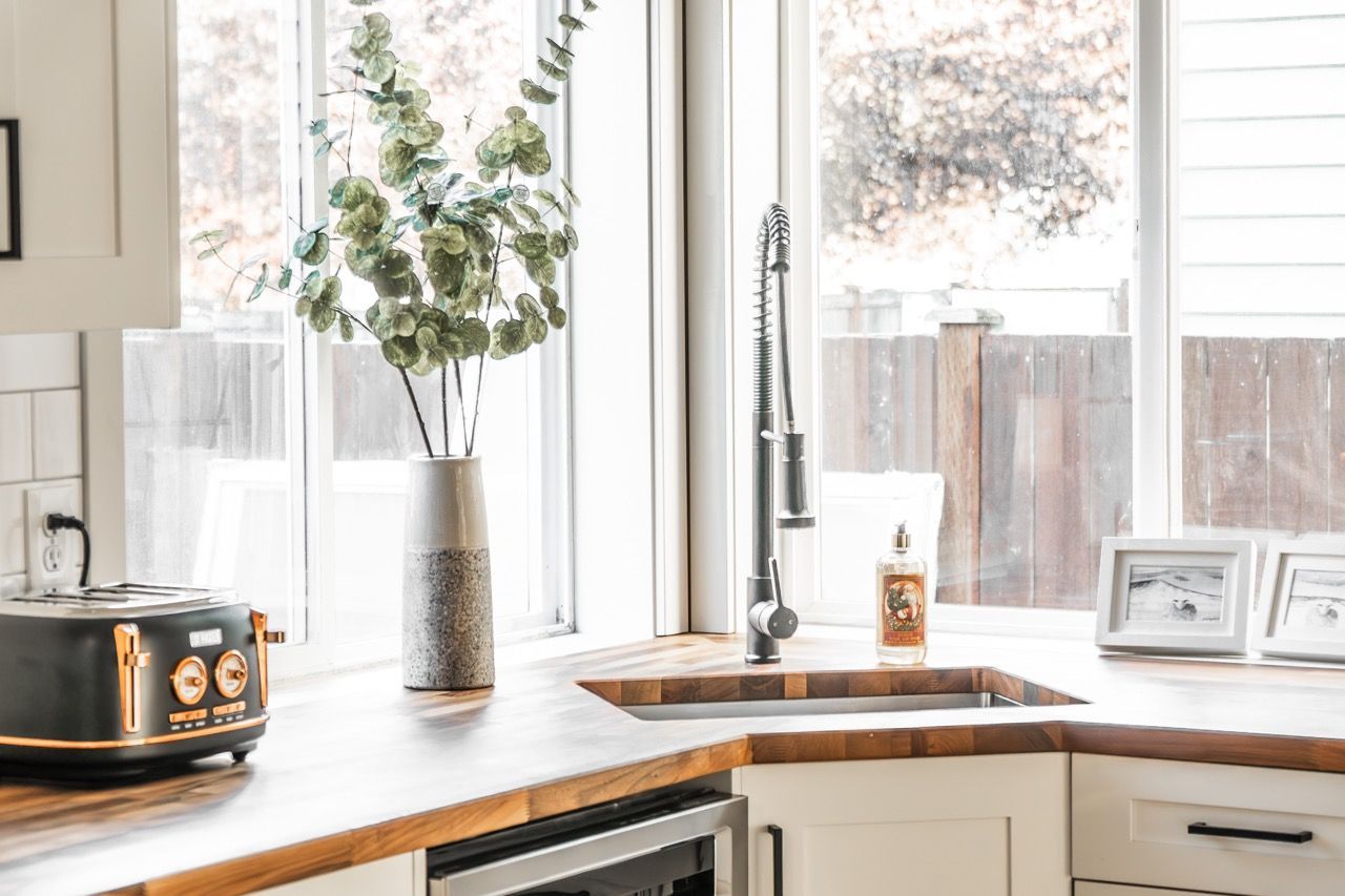 A kitchen with a sink , dishwasher , toaster oven , and window.